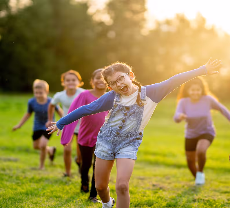 Children running and playing outdoors in a grassy field
